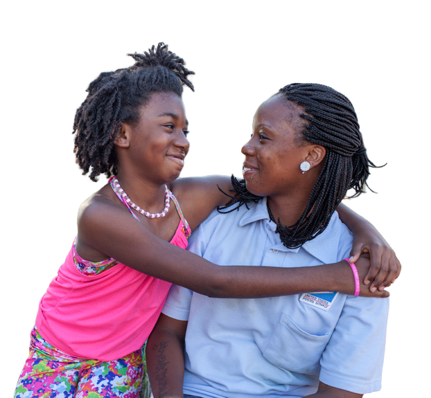 A mother and daughter embracing and smiling at each other outside their home